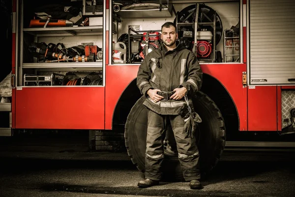 Bombeiro alegre perto de caminhão com equipamento — Fotografia de Stock