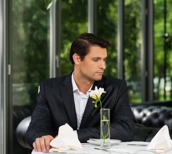 Knappe man in jas wachten iemand in restaurant — Stockfoto