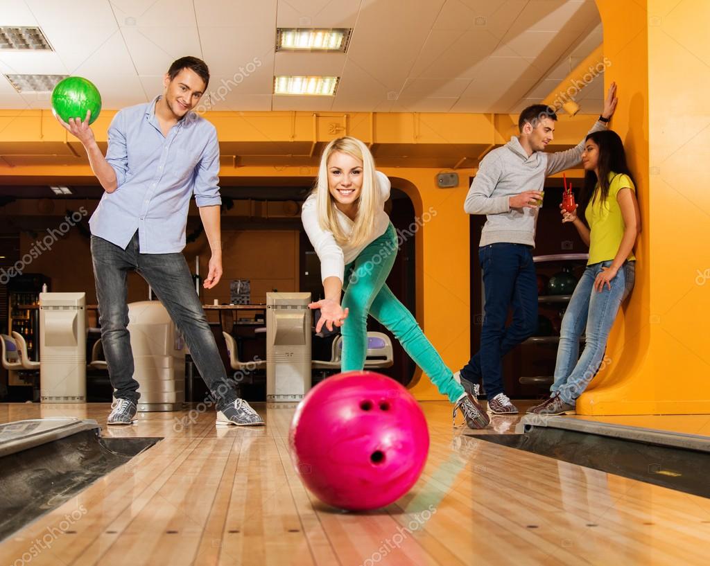 Blond smiling girl throwing ball in a bowling club — Stock Photo