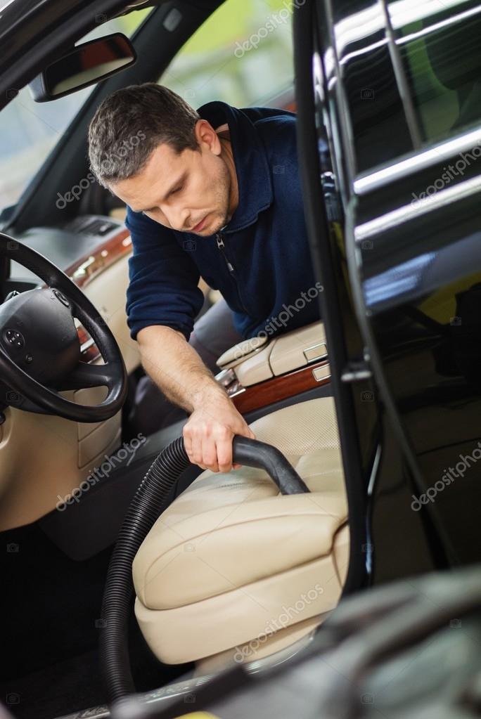 Worker on a car wash cleaning car interior with vacuum cleaner — Stock