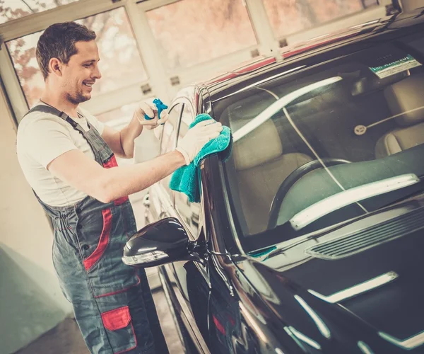 Arbeiter in einer Waschanlage reinigt Auto mit Spray — Stockfoto