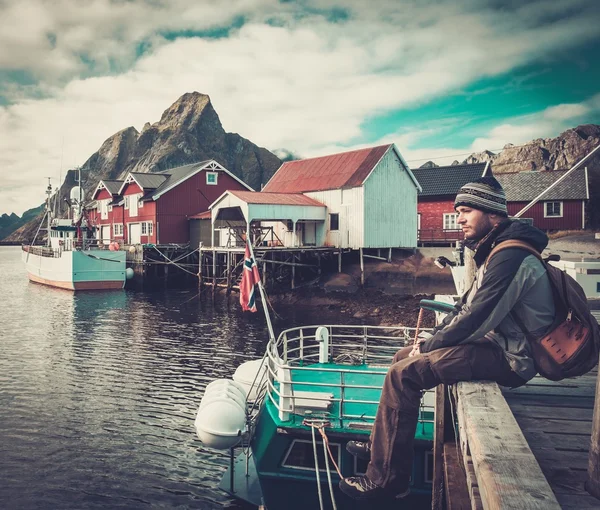 Человек-путешественник, сидящий на пирсе в деревне Рейне, Норвегия — стоковое фото