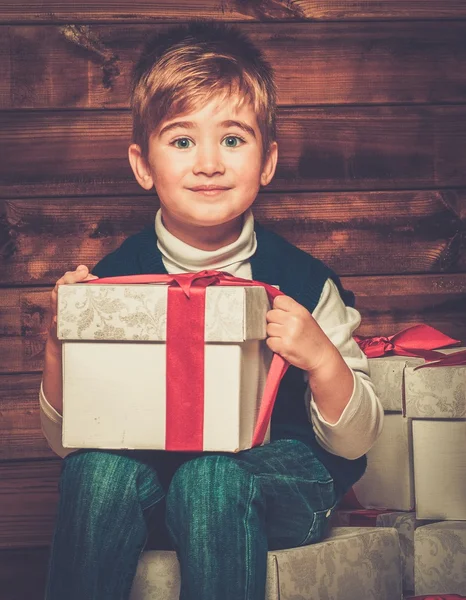 Liten pojke med presentask under granen i trähus inre — Stockfoto