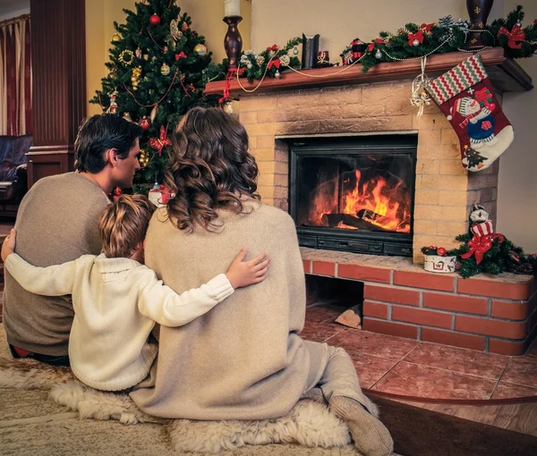 Family near fireplace in Christmas decorated house interior — Stock Photo, Image