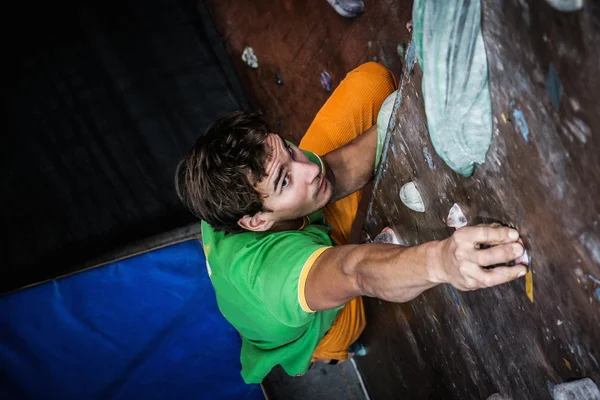 Muscular man practicing rock-climbing on a rock wall indoors — Stock Photo, Image