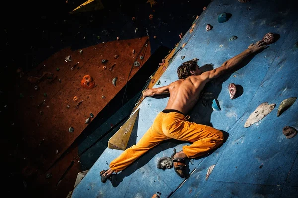 肌肉男在室内的岩壁上练习攀岩 — 图库照片
