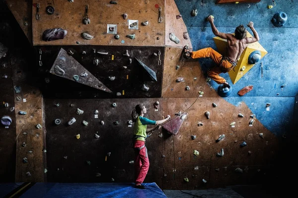 Muscular man practicing rock-climbing on a rock wall indoors — Stock Photo, Image