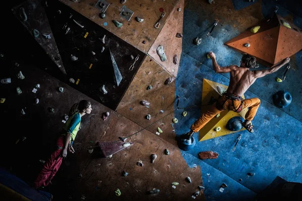 Muscular man practicing rock-climbing on a rock wall indoors — Stock Photo, Image