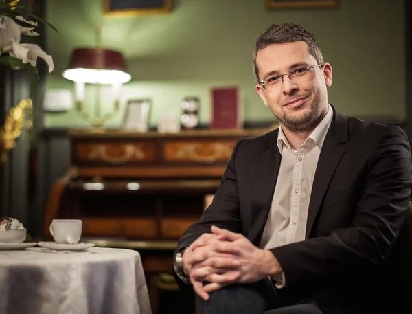 Middle-aged man behind table in luxury vintage style interior — Stock Photo, Image