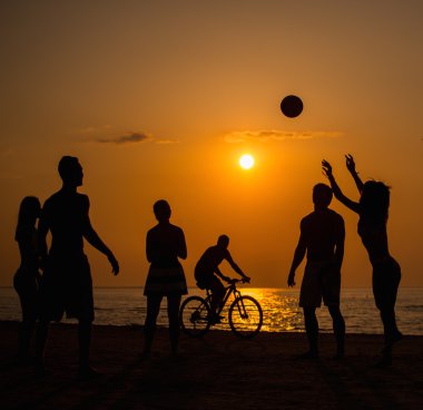Silhouettes a young people playing with ball on a beach   clipart