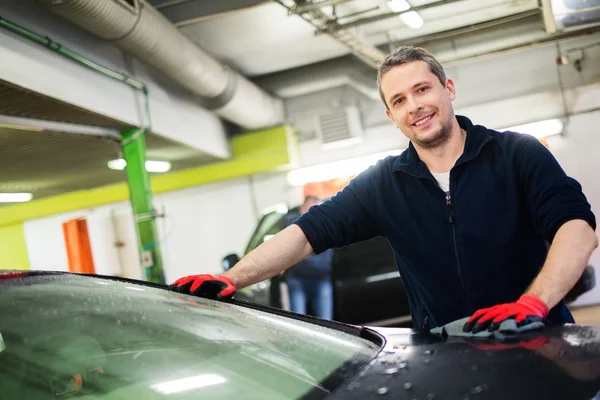 Trabajador alegre limpiando el coche en un lavado de coches — Foto de Stock