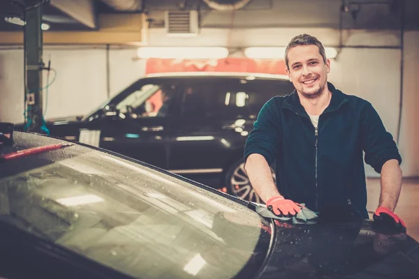 Trabajador alegre limpiando el coche en un lavado de coches — Foto de Stock