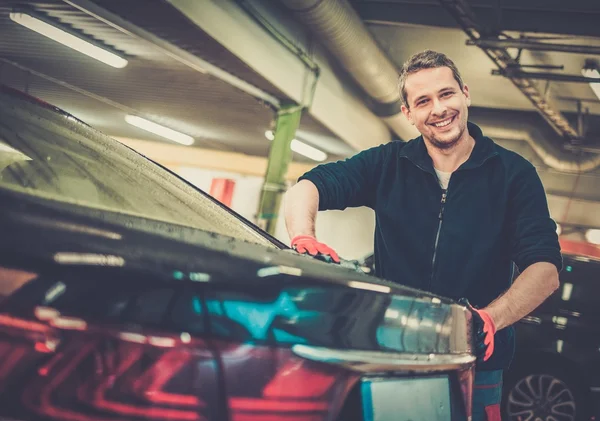 Trabajador alegre limpiando el coche en un lavado de coches —  Fotos de Stock