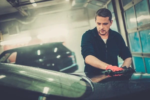 Cheerful worker wiping car on a car wash — Stock Photo, Image