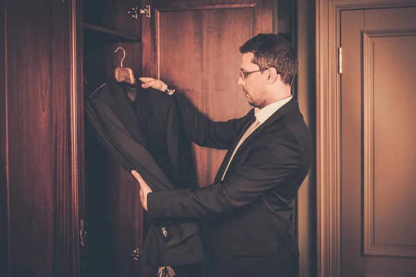 Middle-aged man taking suit from wardrobe