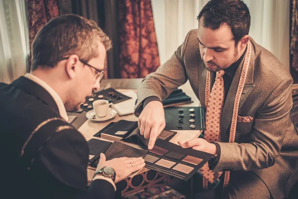 Sastre y cliente eligiendo tela y botones para traje hecho a medida — Foto de Stock