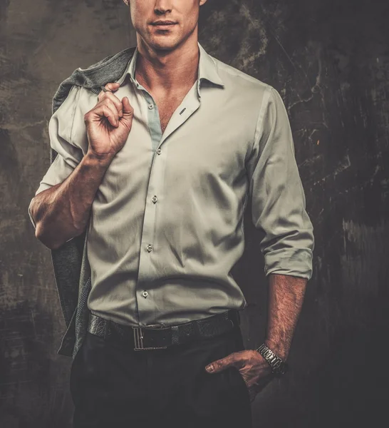 Hombre guapo en camisa contra pared grunge sosteniendo chaqueta sobre el hombro — Foto de Stock