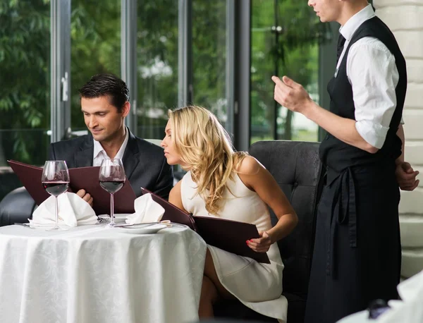 Cheerful couple with menu in a restaurant making order — Stock Photo, Image