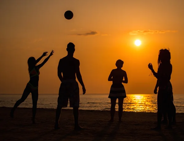 Σκιαγραφίες μια νέοι άνθρωποι που παίζουν με την μπάλα σε μια παραλία — Φωτογραφία Αρχείου
