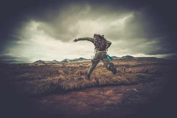 Man hiker jumping across small river — Stock Photo, Image