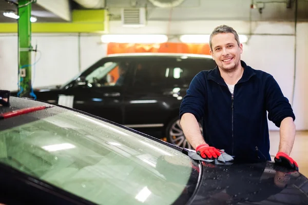 Trabajador limpiando coche en un lavado de coches — Foto de Stock