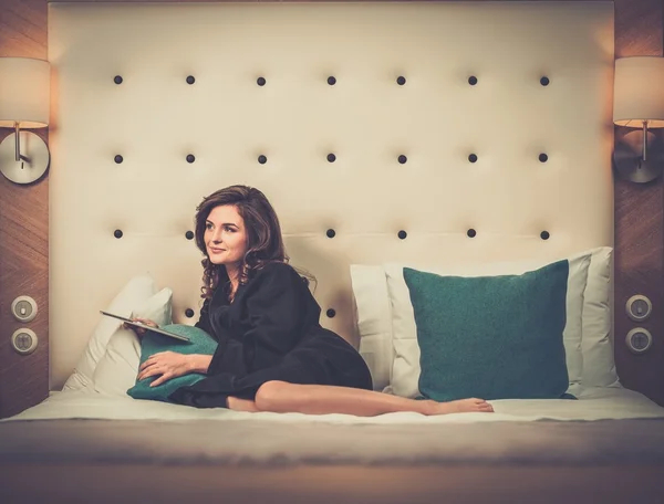 Mujer acostada en una cama con tablet pc —  Fotos de Stock