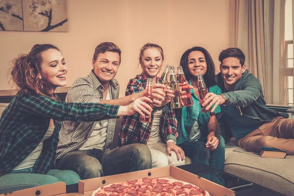 Multi-etnische vrienden met pizza en flessen van drank thuis vieren — Stockfoto