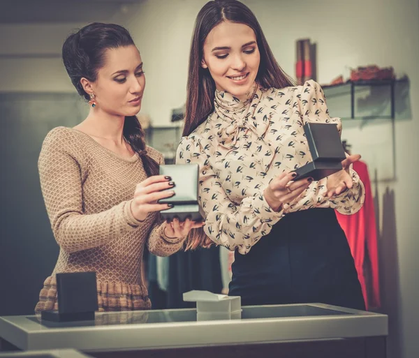 Joven mujer eligiendo joyas con ayuda de asistente de tienda — Foto de Stock