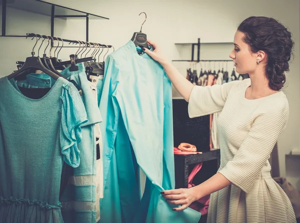 Giovane donna che sceglie i vestiti su un rack in uno showroom — Foto Stock