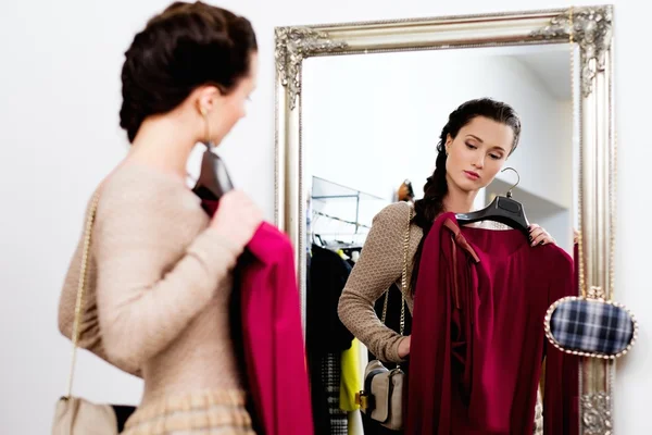 Mujer joven eligiendo ropa en una sala de exposición —  Fotos de Stock