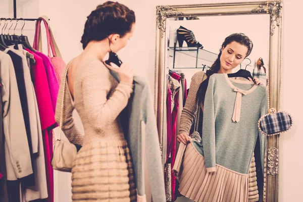 Mujer joven eligiendo ropa en una sala de exposición — Foto de Stock