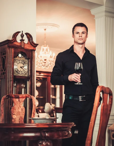 Uomo ben vestito in interni casa di lusso con vino di vetro — Foto Stock