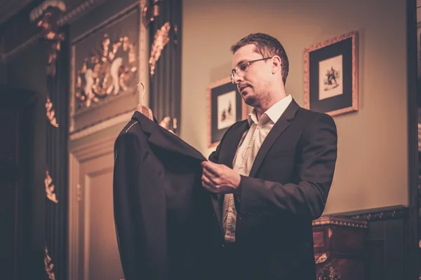 Mann mittleren Alters betrachtet Anzug auf Kleiderbügel — Stockfoto