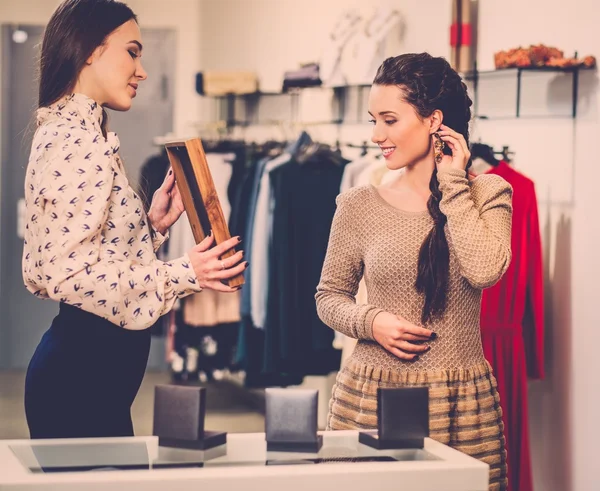 Joven mujer eligiendo joyas con ayuda de asistente de tienda —  Fotos de Stock