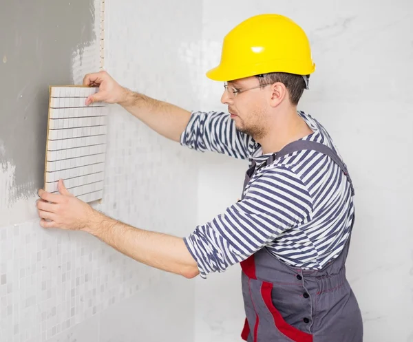 Construtor aplicando telha em uma parede — Fotografia de Stock