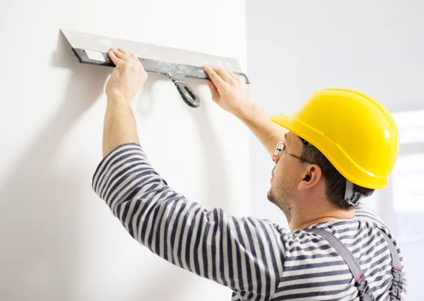 Builder levelling wall with spatula — Stock Photo, Image