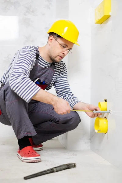 Bauarbeiter misst Rohr im Badezimmer — Stockfoto