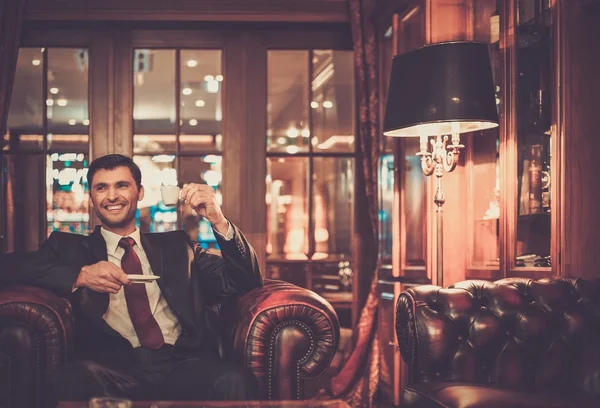 Homem sentado com uma xícara de café em um interior de luxo — Fotografia de Stock