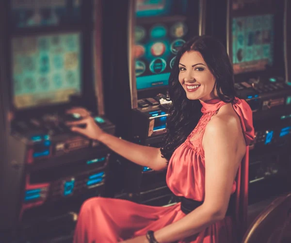 Donna in abito rosso giocare a slot machine — Foto Stock