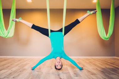 Young woman performing antigravity yoga exercise clipart