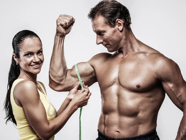 Vrouw meten atletische-man biceps — Stockfoto