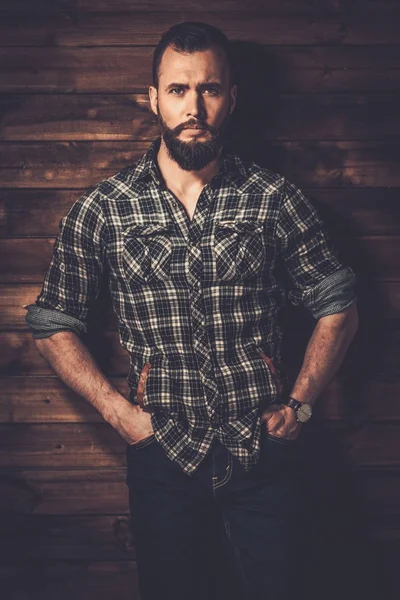 Man in checkered shirt, wooden house interior — Stock Photo, Image