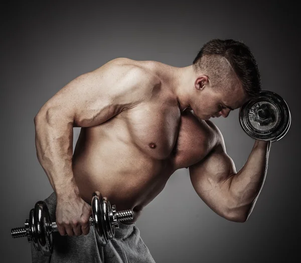 Muscular man exercising with dumbbells — Stock Photo, Image