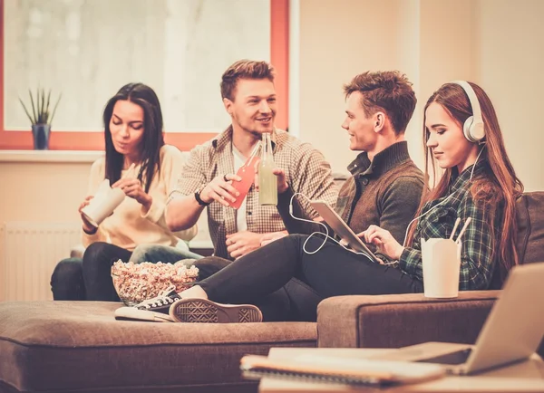 Grupp av glada studenter med drinkar och popcorn i heminredning — Stockfoto