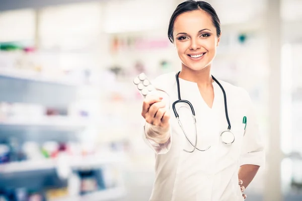 Позитивна брюнетка лікарка тримає таблетки в аптеці — стокове фото