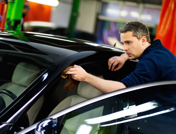 Чоловік працівник полірує машину на автомийці — стокове фото