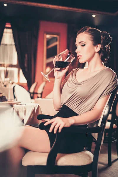 Jovem com copo de vinho tinto sozinha em um restaurante — Fotografia de Stock