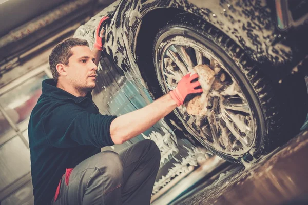 Férfi munkás mosás autó ötvözet kerekek egy autómosó — Stock Fotó