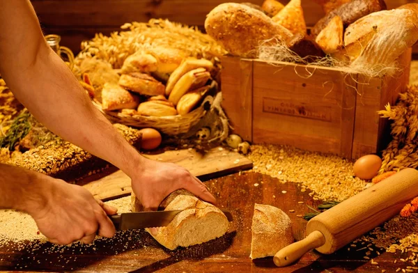 Человек режет домашний хлеб на столе — стоковое фото