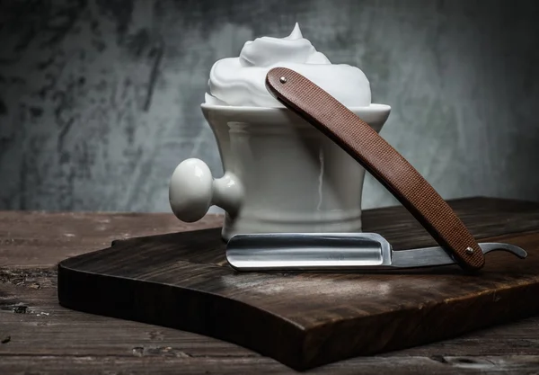 Бритвы и миска с пеной на деревянном фоне — стоковое фото